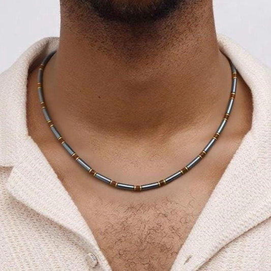 Man wearing hematite tube-bead necklace on his neck, white knit shirt