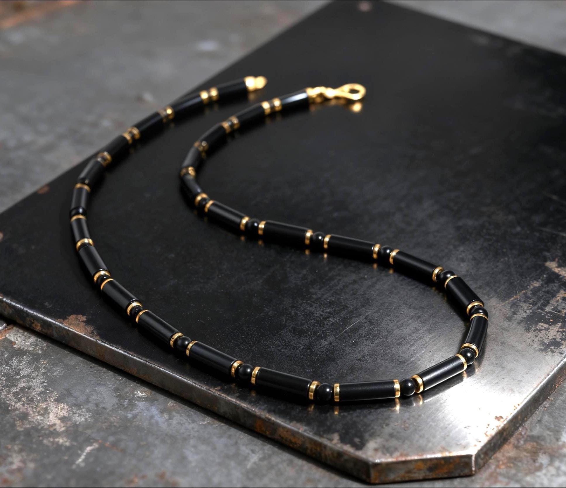 Black beaded necklace with gold accents on a dark metal surface